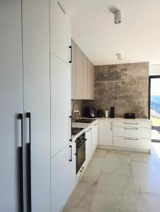 a white kitchen with white cabinets and appliances at Bacówki Resort in Ochotnica Górna