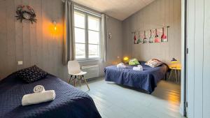 1 Schlafzimmer mit 2 Betten, einem Tisch und einem Stuhl in der Unterkunft Charmante maison de village in Le Bois-Plage-en-Ré