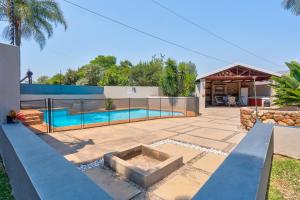 un patio trasero con piscina y una casa en The Bosau Guest House, en Pretoria