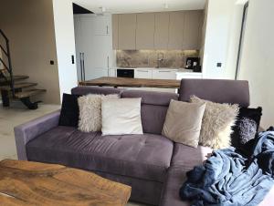 a purple couch in a living room with a kitchen at Bacówki Resort in Ochotnica Górna