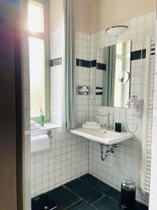 La salle de bains est pourvue d'un lavabo et d'un miroir. dans l'établissement Gästehaus Schönitz, à Meissen