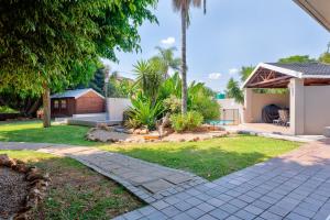 a yard with a house and a garden with a patio at The Bosau Guest House in Pretoria