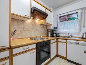 uma cozinha com armários brancos e um forno com placa de fogão em Holiday home in Langscheid with panoramic view em Langscheid