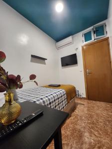 Habitación pequeña con cama y mesa con jarrón en M-A Catrachos Rooms, en Madrid