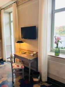 Zimmer mit einem Schreibtisch, einem TV und einem Fenster in der Unterkunft Gästehaus Schönitz in Meißen
