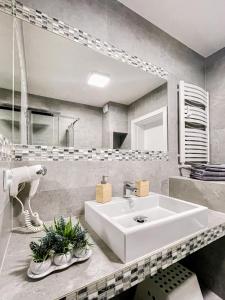 La salle de bains est pourvue d'un lavabo blanc et d'un miroir. dans l'établissement Sandy Apartment Deluxe Horyzont Międzyzdroje, à Międzyzdroje