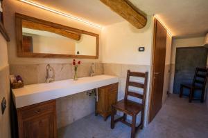 a bathroom with a sink and a wooden chair at Baita Eleonora in Argegno