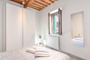 a white bedroom with a bed and a window at Piombino Apartments - Casa XX Settembre in Piombino