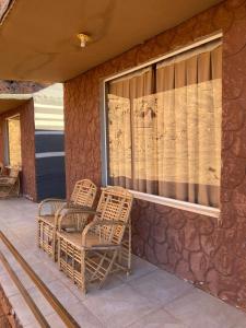 two wicker chairs sitting on the porch of a house at Diamond Wadi Rum Luxury Camp in Wadi Rum