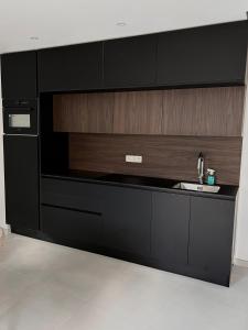 a kitchen with black cabinets and a sink at Phoenix garden in Mons