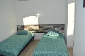2 camas en una habitación con sábanas y almohadas verdes en Gîte de LANVIAN en Guissény
