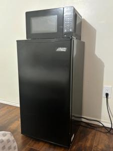 Un four micro-ondes est installé au-dessus d'un réfrigérateur noir. dans l'établissement Bright Queen Room, à Brampton