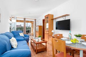 a living room with a blue couch and a table at Villa Sol Menorca in Punta Prima