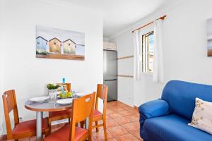 a living room with a table and a blue couch at Villa Sol Menorca by Escape Home in Punta Prima