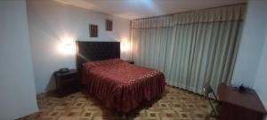 1 dormitorio con 1 cama con colcha roja en HOTEL F0NTEs GLOBAL, en Tacna