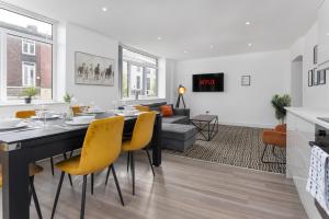 a dining room and living room with a table and yellow chairs at Flatzy - 16 Guests 4 En-suite Central Apartment A in Liverpool