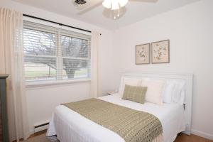 a white bedroom with a bed and a window at Inglewood Cottage 