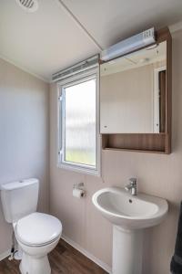 a bathroom with a toilet and a sink and a window at CALI - 3Bed - Static Caravan in Port Seton