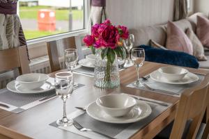 a wooden table with a vase of pink flowers on it at CALI - 3Bed - Static Caravan in Port Seton
