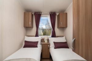 two beds in a small room with a window at CALI - 3Bed - Static Caravan in Port Seton
