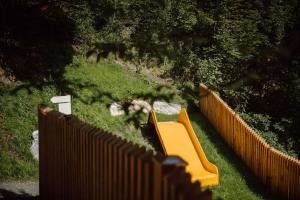 a playground with a yellow bench next to a fence at TheResi Appartements in Saalbach-Hinterglemm