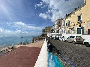 una calle con coches estacionados junto al océano en Casa vacanza: The Wind Rose, en Vietri