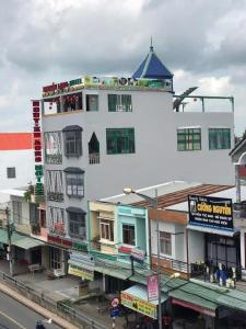 un gran edificio blanco con un avión volando sobre una calle en KHÁCH SẠN NGUYỄN LONG en Thap Muoi