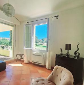 ein Wohnzimmer mit einem großen Fenster und einem Stuhl in der Unterkunft VILLA DANS CADRE D'EXCEPTION - GOLF, PISCINE ET TENNIS PRIVE in Saint-Cyr-sur-Mer