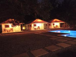 a couple of tents with a swimming pool at night at Torch Ginger Homestay in Sultan Bathery