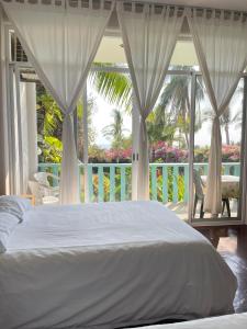 ein Schlafzimmer mit einem weißen Bett und einem Balkon in der Unterkunft Siete Mares in Brisas de Zicatela