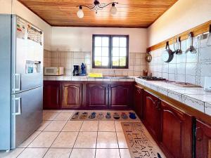 cocina con armarios de madera y nevera en Maison de 3 chambres avec vue sur la mer terrasse amenagee et wifi a Saint Leu, en Saint-Leu