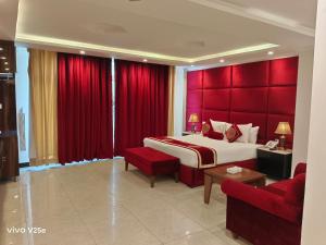 a bedroom with a large bed and red curtains at Falettis Grand Hotel Murree in Murree