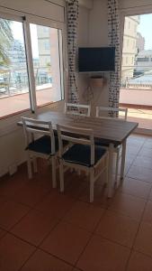 un tavolo in legno con due sedie e una televisione di APCOSTAS - Puerto Simona a Roses