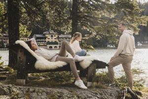 a group of people sitting on a bench by the water at Seehotel Jägerwirt in Turracher Hohe