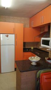 - une cuisine avec des armoires orange et un réfrigérateur blanc dans l'établissement Estudio con acceso privado y directo a la Playa, à Isla Cristina