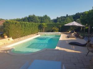 einen Pool im Hinterhof mit Sonnenschirm in der Unterkunft Maison Cloé in Turnac