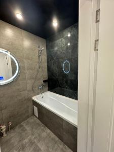 a bathroom with a bath tub and a mirror at ЖК Комсомольский in Taldykolʼ