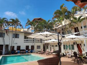 - une piscine avec des chaises et des parasols à côté d'un bâtiment dans l'établissement Pousada Estalagem dos Corais da Prainha, à Arraial do Cabo