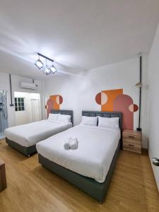 two beds in a room with white and orange at Madi Betong Homestay (มาดีเบตง) in Betong