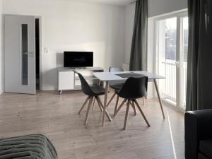 a living room with a table and chairs and a television at Board Inn - Haus Regensburg in Regensburg