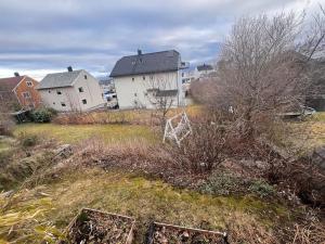 an empty field with houses and trees and grass at Cozy one-bedroom with a view in Molde