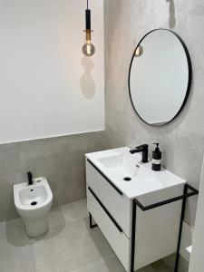 ein Badezimmer mit einem Waschbecken, einem Spiegel und einem WC in der Unterkunft Baaria house in Bagheria