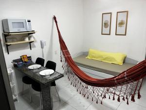 a hammock bed in a room with a table at Charme do Residence in Natal