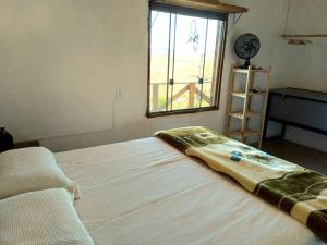 - un lit avec couverture dans une chambre avec fenêtre dans l'établissement Casinha do Milho - Visual único!, à Milho Verde