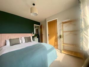 a bedroom with a large bed and a green wall at Beautiful 3 Bedroom Home, North Cornwall in Saint Teath