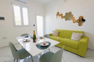 ein Wohnzimmer mit einem Tisch und einer gelben Couch in der Unterkunft Salentin Home - WindRelax in San Pietro in Bevagna