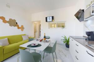 ein Wohnzimmer mit einem grünen Sofa, einem Tisch und Stühlen in der Unterkunft Salentin Home - WindRelax in San Pietro in Bevagna + 11 Fotos