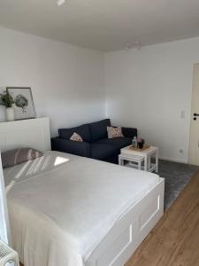 a bedroom with a white bed and a blue couch at Gemütliches Appartement nahe Universitätsklinik in Magdeburg