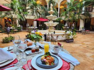 a table with a plate of food in front of a fountain at Mansión Mérida Boutique Hotel - Restaurant in Mérida