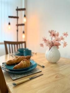 a table with a plate of croissants and a vase at Cosy Prenton home near Tranmere Club and Liverpool in Birkenhead